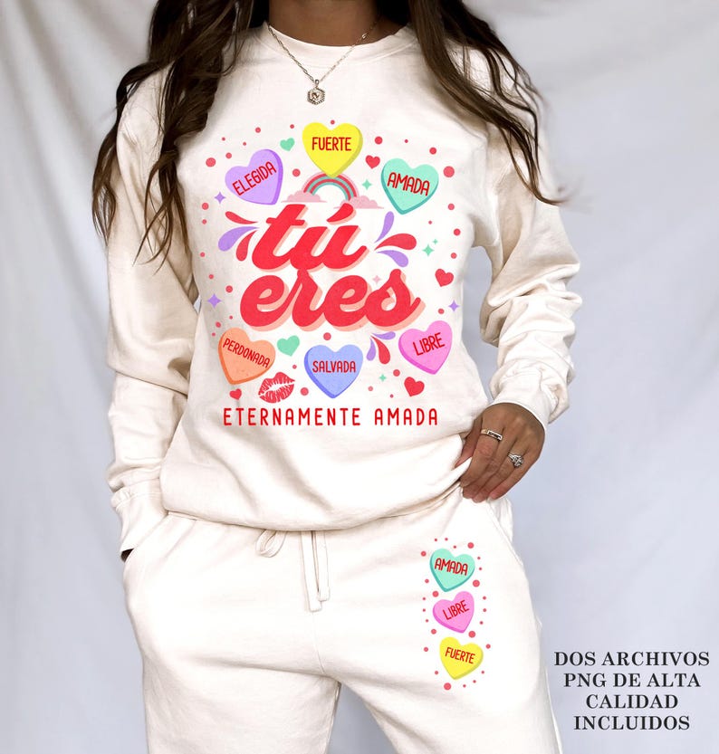 May include: A white sweatshirt with a graphic design of colorful hearts with Spanish text that reads "tu eres" and "eternamente amada".