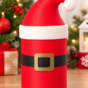Puede incluir: Una caja de regalo cilíndrica diseñada para parecerse a un traje de Papá Noel. El recipiente es de color rojo brillante con un cinturón negro que presenta una hebilla cuadrada dorada en el centro y un borde blanco texturizado.