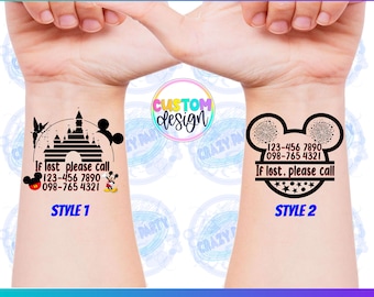 May include: Two temporary tattoo designs for kids. The first design features a black silhouette of Cinderella's castle with Mickey Mouse ears on either side. The text reads "If lost please call 123-456 7890 098-765 4321" and "Style 1". The second design features a black silhouette of Mickey Mouse ears with fireworks inside. The text reads "If lost, please call 123-456 7890 098-765 4321" and "Style 2".