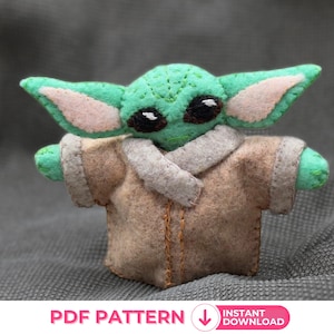 Könnte beinhalten: Ein grünes Plüschtier aus Filz, das einen Charakter aus dem Star Wars-Franchise darstellt, trägt einen braunen Filzmantel. Das Spielzeug hat große Ohren und große Augen. Das Spielzeug sitzt auf einer grauen, strukturierten Oberfläche. PDF PATTERN INSTANT DOWNLOAD