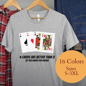Puede incluir: Camiseta gris con un gráfico de cuatro cartas de juego, un As de Picas, un As de Corazones, un Rey de Corazones y una Reina de Corazones. El texto en la camiseta dice "4 Cards Are Better Than 2 (If You Know You Know)". La camiseta está disponible en 16 colores y tallas S-3XL.
