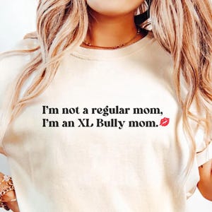 May include: A white t-shirt with the text "I'm not a regular mom, I'm an XL Bully mom." and a red lip print.