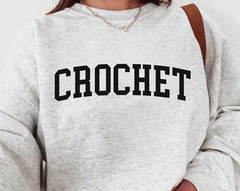 Puede incluir: Una sudadera gris con la palabra "CROCHET" impresa en letras negras.