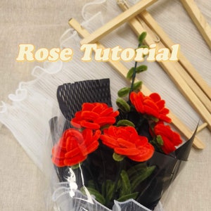 May include: A bouquet of red velvet roses wrapped in black and white tissue paper. The roses are arranged in a clear plastic bag. The text "Rose Tutorial" is visible at the top of the image.