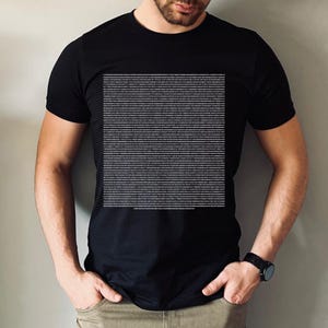 Könnte beinhalten: Ein schwarzes T-Shirt mit einem weißen grafischen Druck eines großen Textblocks. Der Text ist in kleiner Schrift und scheint Code zu sein.