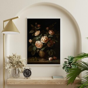 May include: A framed floral still life painting featuring a bouquet of peach and cream roses in a decorative vase. The dark background highlights the flowers and green leaves. The painting is displayed on a wooden shelf with a clock and other decor.