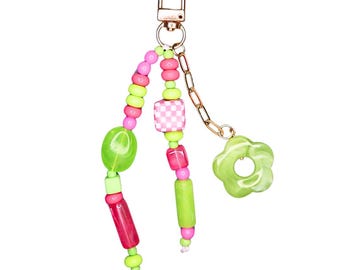 May include: A green and pink beaded keychain with a gold chain and a green flower charm.