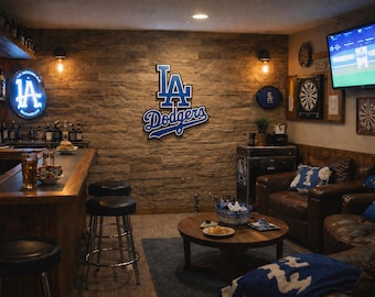 Puede incluir: Una habitación temática deportiva con bar, asientos y decoración mural. El logotipo de Los Angeles Dodgers es prominente. La habitación incluye un bar con taburetes, un televisor y una diana, creando un espacio para el entretenimiento.