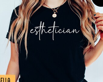 Op de afbeelding: Zwart T-shirt met het woord "esthetician" in witte letters. Het shirt heeft een ronde hals en korte mouwen. De merknaam "Bella Canvas" staat op een gele vierkant linksonder. Een zwarte cirkel met het woord "BLACK" staat rechtsboven.