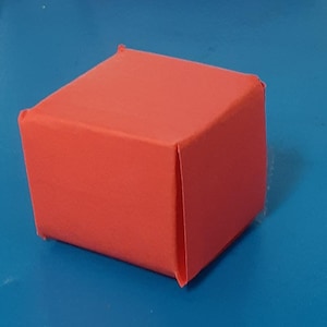 Pode incluir: Uma pequena caixa retangular vermelha feita de papel.