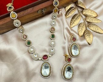 May include: A gold necklace and earrings set with a teardrop pendant and clear stones. The necklace has a multi-colored stone design.