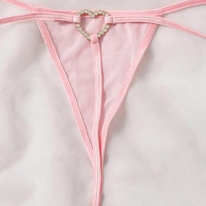 Puede incluir: Lingerie rosa con un detalle de corazón de pedrería.