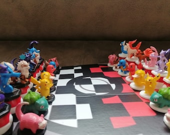 May include: A colorful Pokémon-themed chess set with a black and red checkered board. The chess pieces are various Pokémon characters in vibrant colors, set up for a game. The board has a large white Pokémon logo.