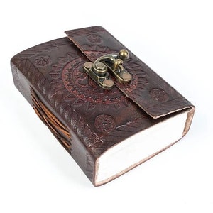 May include: A brown leather journal with a decorative embossed design and a brass clasp closure.