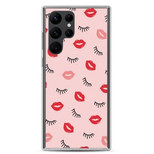 May include: A clear phone case with a pink background and a repeating pattern of red lips and black eyelashes.