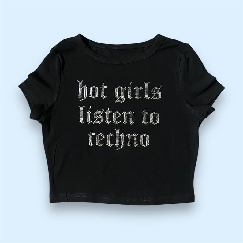 Pode incluir: Camiseta preta de manga curta e corte cropped com o texto "hot girls listen to techno" em strass prateados.
