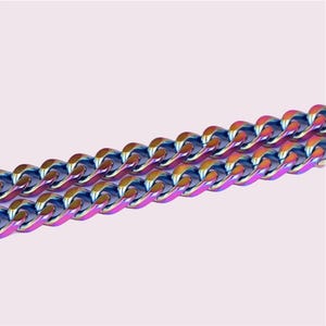 May include: A close-up of a rainbow-colored curb chain necklace. The chain is made of metal and has a shiny finish.