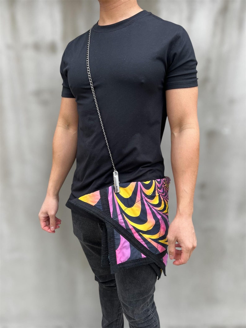 May include: A black t-shirt with a silver chain and a pink, yellow, and black patterned bandana tied around the waist.