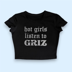 May include: A black short-sleeved crop top featuring the text "hot girls listen to GRIZ" written in a silver-toned, rhinestone-embellished font across the centre of the chest. The garment has a round neckline and a straight hemline.