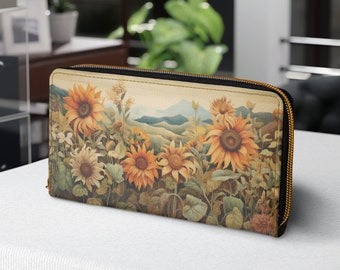 May include: A brown leather zippered wallet with a colorful sunflower print. The print features a field of sunflowers with a mountain range in the background.