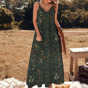 May include: A dark green maxi dress with a floral pattern. The dress has a V-neck and thin straps. The floral pattern includes shades of green, brown, and cream. The dress is worn outdoors.