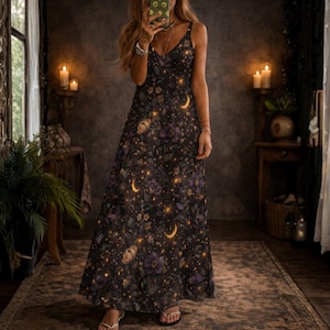 Könnte beinhalten: Ein schwarzes Maxikleid mit floralem und himmlischem Druck. Das Kleid hat einen V-Ausschnitt und Spaghettiträger. Das Design umfasst lila Blumen, Halbmonde und leuchtende Sterne. Das bodenlange Kleid ist für verschiedene Anlässe geeignet.