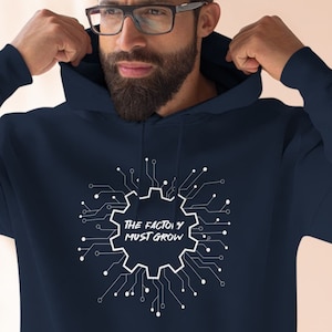 May include: Navy blue hoodie with a white graphic of a gear with circuit board lines and the text "The factory must grow".