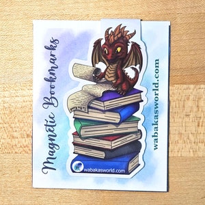 May include: A red dragon bookmark with a stack of books and a scroll. The bookmark is a magnetic bookmark and has the text "wabakasworld.com" on it. The text "Magnetic Bookmarks" is on the left side of the image.
