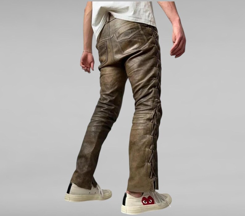 May include: Brown leather pants with a lace-up detail on the sides. The pants are worn with white sneakers.