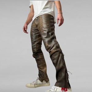 May include: Brown leather pants with a lace-up detail on the side seams. The pants are worn with white sneakers.