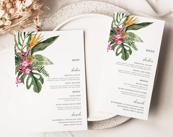 May include: Two white menu cards with floral watercolor designs. The cards feature tropical flowers, including birds of paradise, orchids, and monstera leaves. The menu text is in a simple, elegant font.