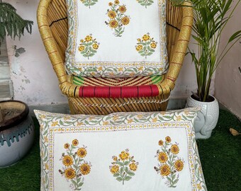 May include: Two white cotton pillow covers with a floral print featuring yellow and brown flowers. The pillow covers have a green and yellow border.