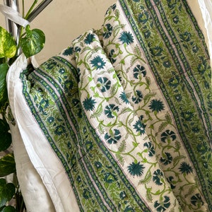 May include: A white and green cotton quilt with a floral pattern. The quilt has a striped design with green and white stripes.