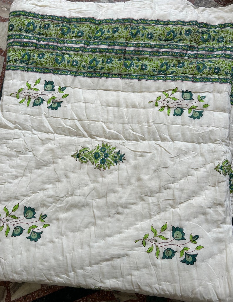 May include: White cotton quilt with a green floral pattern. The quilt has a border of green floral designs.