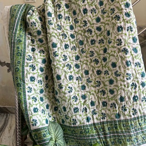 May include: A white cotton quilt with a green floral pattern. The quilt has a border of green stripes.