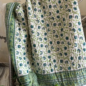 May include: A white cotton quilt with a green floral pattern. The quilt has a border of green stripes.
