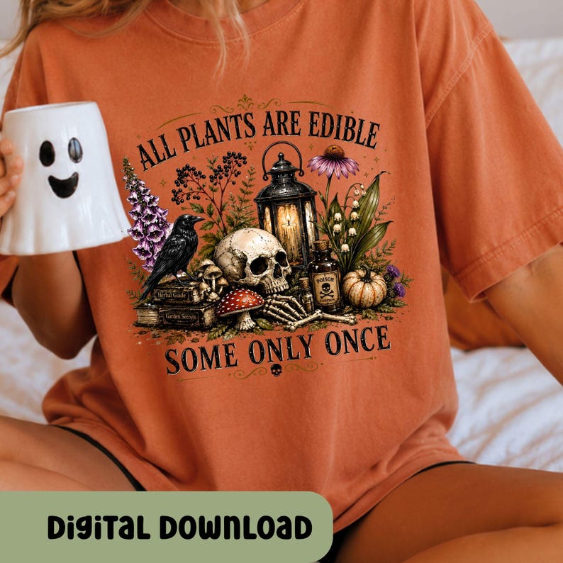 Puede incluir: Una camiseta color naranja quemado con un estampado gr&aacute;fico de una calavera, un cuervo negro, un farol, una botella peque&ntilde;a con la etiqueta poison, setas y flores. El texto dice ALL PLANTS ARE EDIBLE SOME ONLY ONCE. Una taza blanca con forma de fantasma.