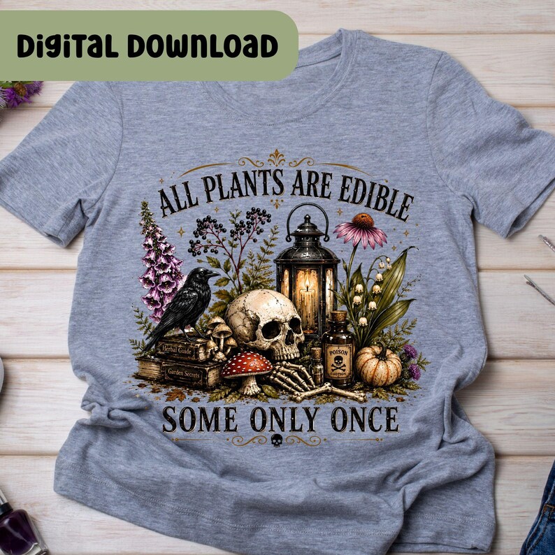 Puede incluir: Una camiseta gris jaspeado con un estampado gr&aacute;fico de un cr&aacute;neo humano, un cuervo negro, una linterna antigua, una botella peque&ntilde;a con la etiqueta poison, una calabaza y varias plantas. El texto dice ALL PLANTS ARE EDIBLE SOME ONLY ONCE.