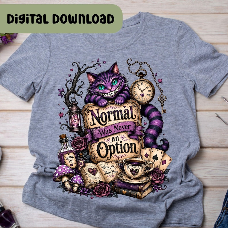 May include: A heather gray t-shirt featuring a graphic of a purple striped cat with green eyes, a pocket watch, a lantern, playing cards, a teacup, and an open book. The text reads, "Normal Was Never an Option" and "Drink Me".