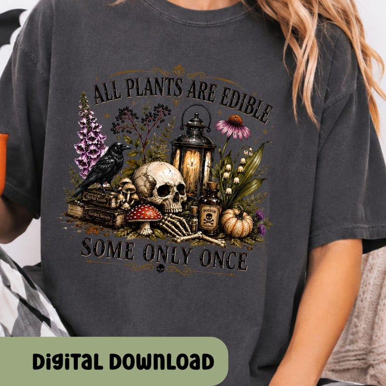 Puede incluir: Una camiseta gris carb&oacute;n con un estampado gr&aacute;fico de una calavera, un cuervo negro, un farol, una botella peque&ntilde;a con la etiqueta poison, setas y flores. El texto dice ALL PLANTS ARE EDIBLE SOME ONLY ONCE. Incluye libros y una calabaza.