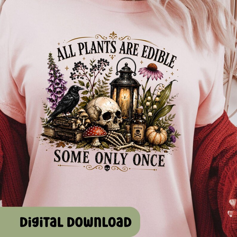 Puede incluir: Una camiseta rosa claro con un estampado gr&aacute;fico que incluye el texto ALL PLANTS ARE EDIBLE SOME ONLY ONCE. El dise&ntilde;o muestra un cuervo negro, un cr&aacute;neo humano, un farol, una botella peque&ntilde;a con la etiqueta POISON, setas y plantas.