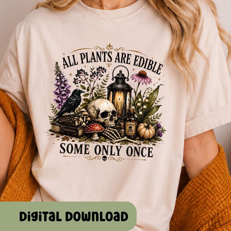 Puede incluir: Una camiseta de color crema con un estampado gr&aacute;fico de una calavera, un cuervo negro, un farol, setas y varias plantas. El texto dice ALL PLANTS ARE EDIBLE SOME ONLY ONCE. El dise&ntilde;o incluye una peque&ntilde;a botella con la etiqueta POISON.