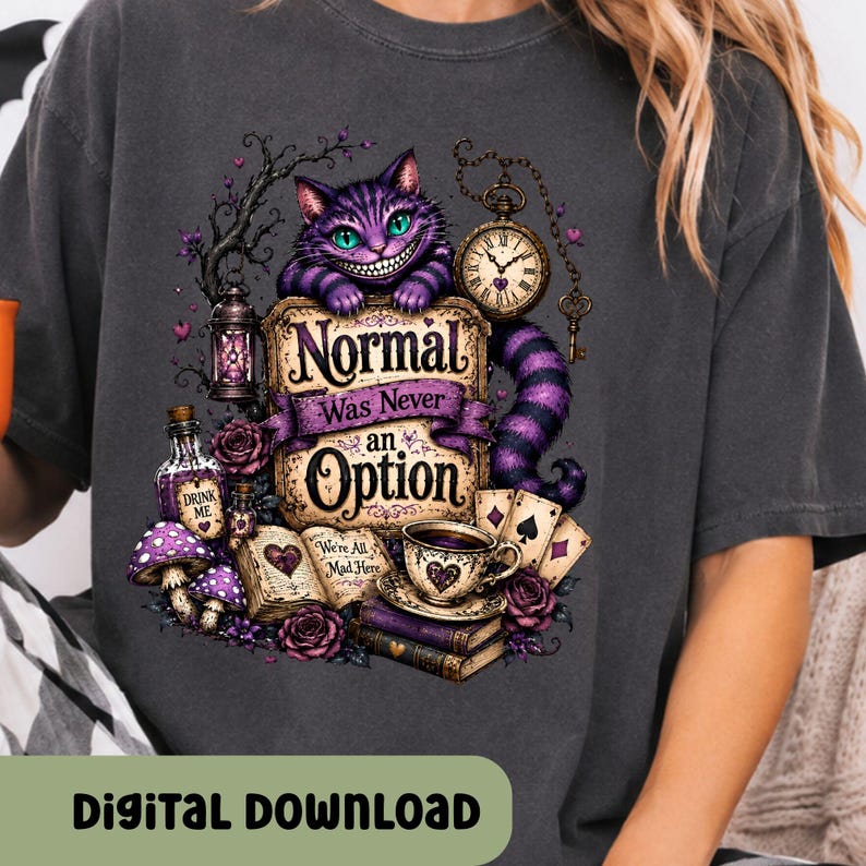 May include: A charcoal gray t-shirt featuring a graphic of a purple striped cat with a wide grin, a pocket watch, a lantern, a bottle labeled Drink Me, an open book with the text We're All Mad Here, and a sign reading Normal Was Never an Option.