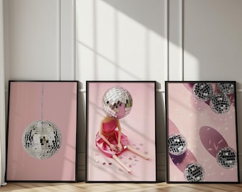 May include: Three framed wall art prints featuring disco ball themes on a pink background. The left print shows a single hanging disco ball. The center print depicts a figure with a disco ball head in a pink dress. The right print shows multiple disco balls.