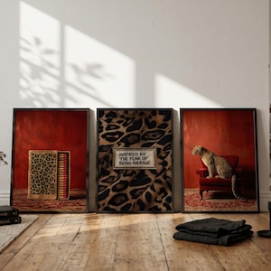 May include: A set of three framed wall art prints. The left print shows a leopard print matchbox. The center print features a leopard pattern background with a rectangular sign reading "INSPIRED BY THE FEAR OF BEING AVERAGE". The right print shows a leopard sitting on a red chair.