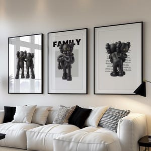 May include: A modern living room featuring a white sectional sofa with black and white accent pillows. Three framed art prints with black and white figures hang above the sofa. A black coffee table and a floor lamp complete the decor.