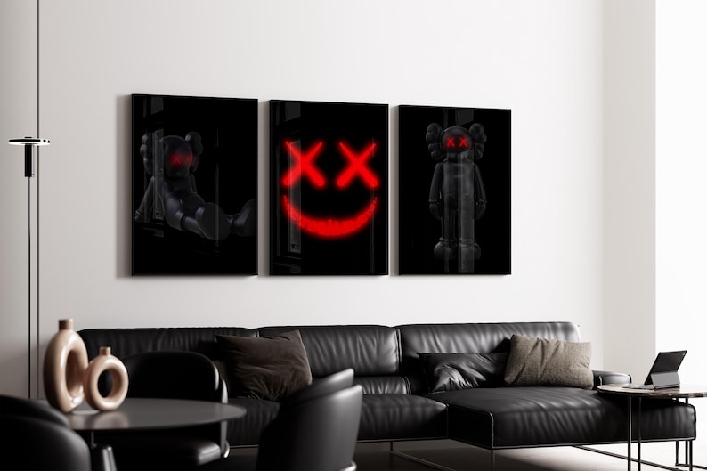K&ouml;nnte beinhalten: Set aus drei schwarzen gerahmten Kunstdrucken mit stilisierten Figuren und einem roten Smiley-Gesicht. Die Drucke werden &uuml;ber einem schwarzen Ledersofa in einem modernen Wohnzimmer pr&auml;sentiert. Die Kunstwerke verleihen dem Raum eine moderne Note.