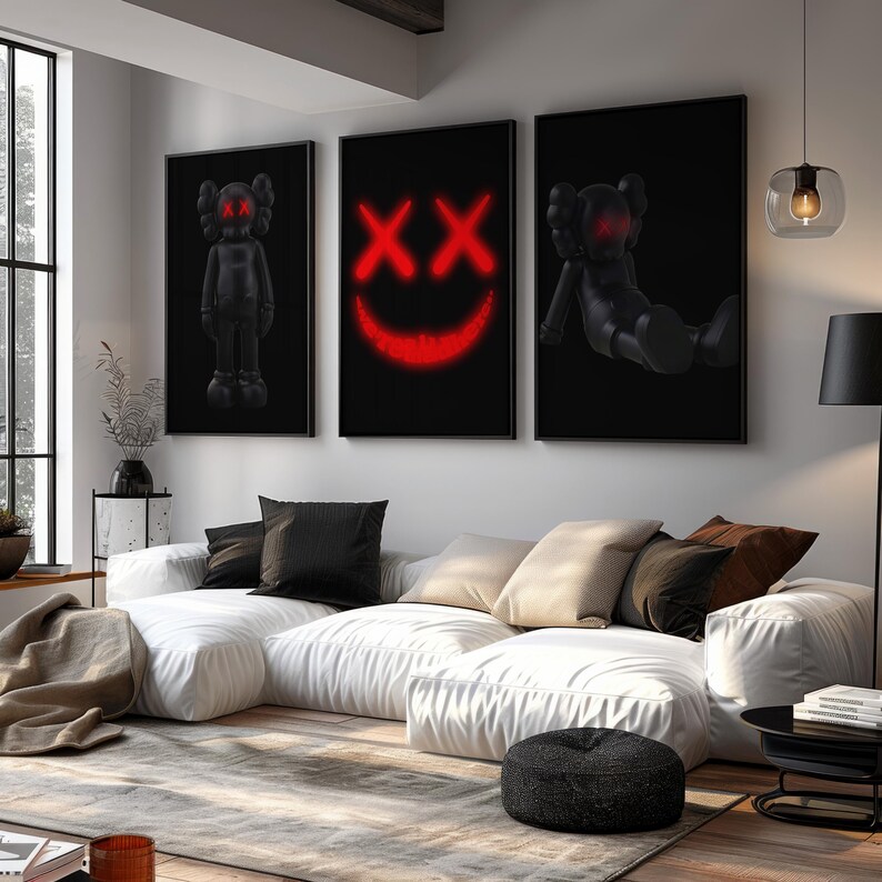 K&ouml;nnte beinhalten: Drei gerahmte schwarze Wandkunstwerke. Eines zeigt eine stehende schwarze Figur mit roten Augen, ein anderes ein rotes Neon-Smiley-Gesicht mit durchgestrichenen Augen und das dritte eine liegende schwarze Figur. Die Kunst h&auml;ngt &uuml;ber einem wei&szlig;en Ecksofa.