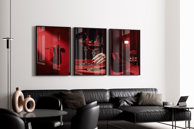 Peut inclure: Trois impressions d'art encadr&eacute;es repr&eacute;sentant un int&eacute;rieur rouge. L'une montre une fen&ecirc;tre avec des rideaux rouges, une autre pr&eacute;sente un cocktail aux cerises, et la troisi&egrave;me montre une lampe et une chaise. Un canap&eacute; en cuir noir et une table avec des vases sont au premier plan.