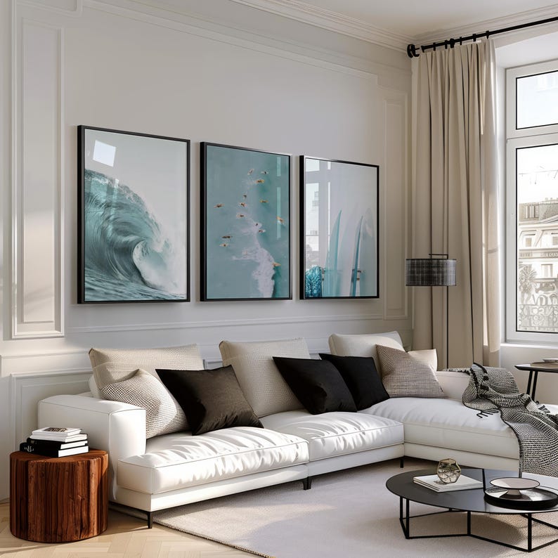 May include: A modern living room featuring a white sectional sofa with black and beige throw pillows. Three framed ocean wave art prints hang above the sofa. A wooden side table and a black coffee table complete the decor.